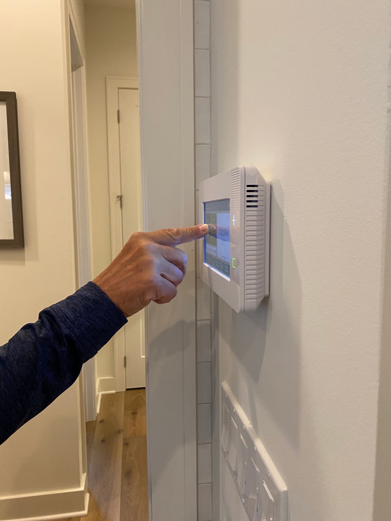 A man is setting his alarm on a security panel in his smart home.