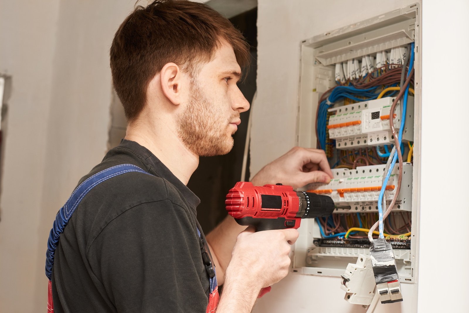 electrician builder engineer screwing equipment in fuse box. electrical installation, repair